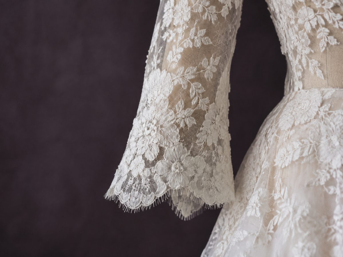 Close detail of a sheer Chantilly lace sleeve with a scalloped eyelash cuff.